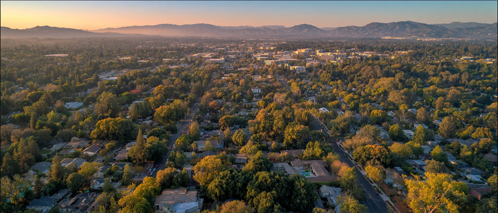 Illustrative aerial view of South Bay neighborhoods at sunset with the Santa Cruz Mountains beyond.